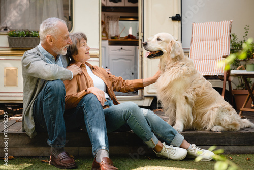Happy old senior caucasian couple spouses traveling with their dog golden retriever labrador in camper van. Holidays with pets. Active wild life photo