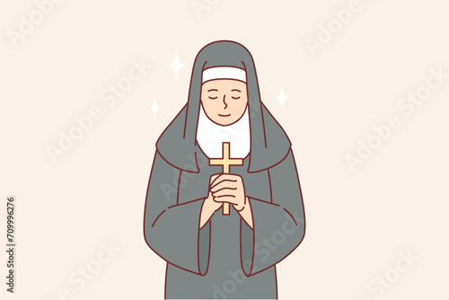 Nun praying holding catholic cross in hands and bowing to god, dressed in cassock
