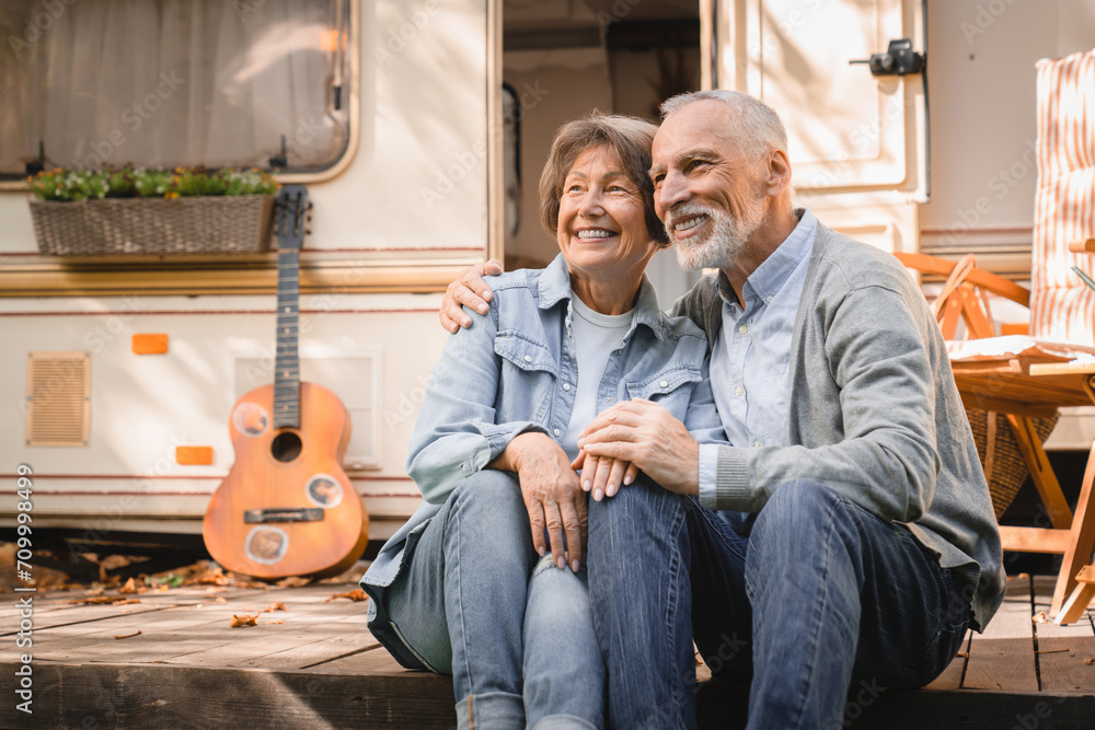 Happy cheerful caucasian senior old couple adventurers explorers hugging embracing while traveling together doing eco-tourism in trailer camper van motor home