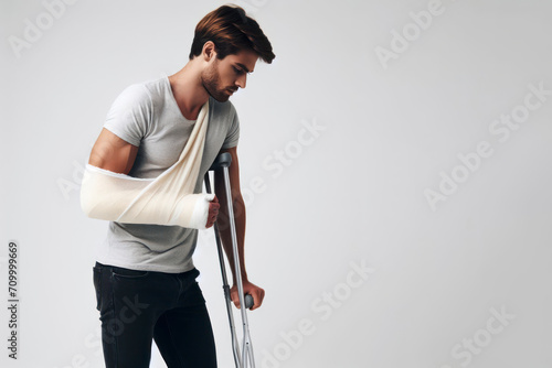 A man with a broken arm in a cast on crutches on a white background. ai generative photo