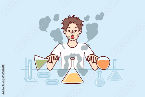 Boy conducts laboratory experiments mixing reagents from test tubes and gets scared having heard explosion. Funny schoolboy in laboratory wants to become chemist and conduct scientific experiments