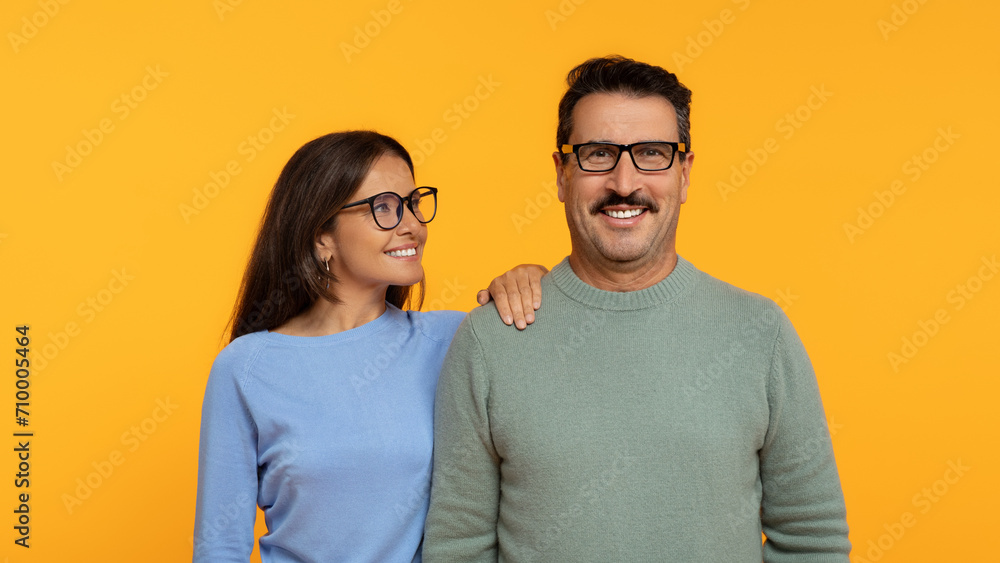 A happy couple stands shoulder to shoulder, the woman wearing glasses A happy couple stands shoulder to shoulder, the woman wearing glasses