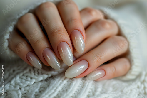  beautiful manicure with almond shape and pearl  milky  white color. against the background of a white sweater