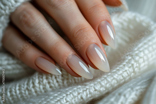  beautiful manicure with almond shape and pearl  milky  white color. against the background of a white sweater
