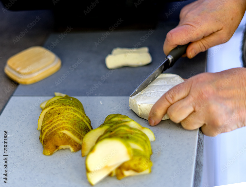 woman cuts pear and camembert to bake woman cuts pear and camembert to bake