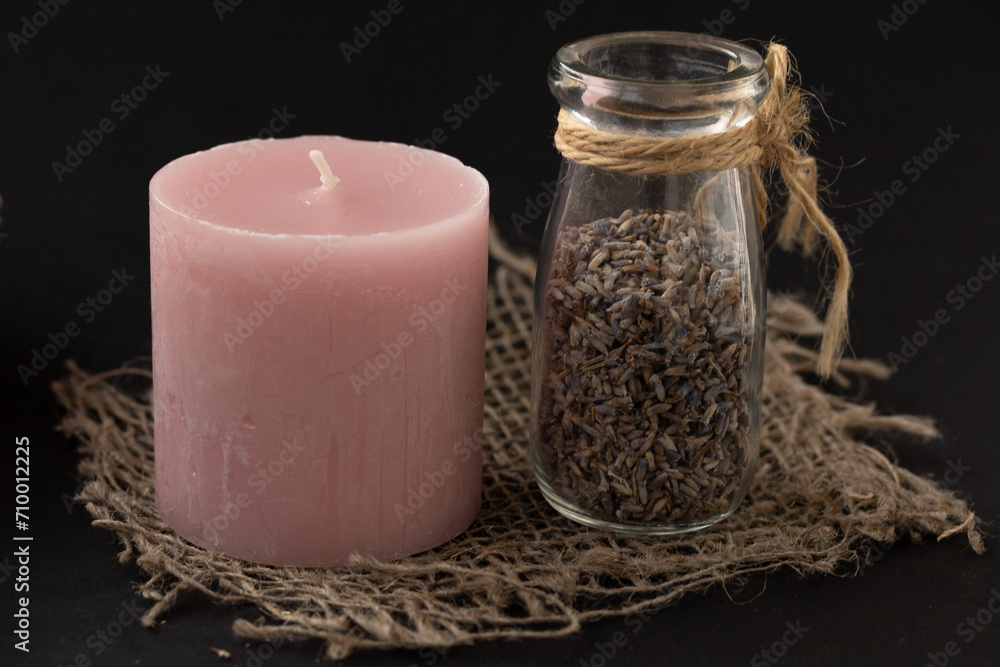 Aromatherapy ingredients, spa concept. Dry aromatic herbs in a glass bottle and candle on dark background. Aromatherapy ingredients, spa concept. Dry aromatic herbs in a glass bottle and candle on dark background.