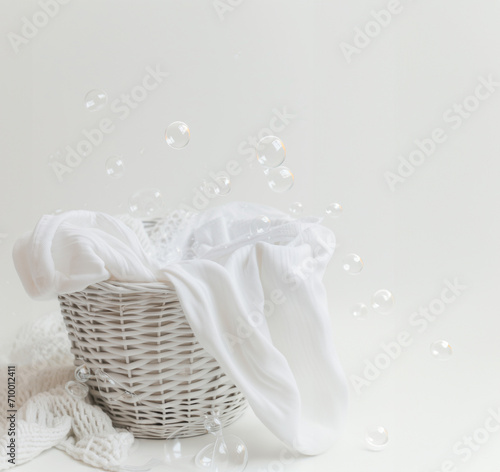 Basket of clean laundry and soap bubbles on white background. Spring cleaning concept, banner with copy space for cleaning service. Poster for laundry.