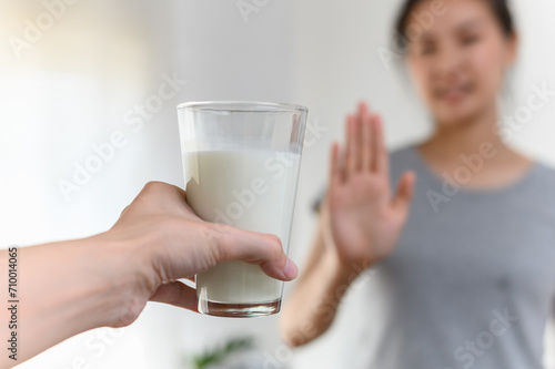 Woman gesturing refusing stop or reject say no glass of milk, Lactose intolerance food allergy and health care concept. photo