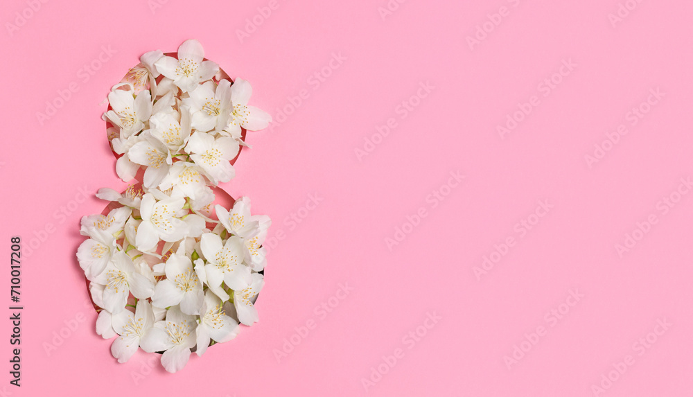 Fototapeta premium White flowers in the shape of the number eight on a pink background. International Women's Day. Postcard for March 8. Banner, flyer. Copy space.