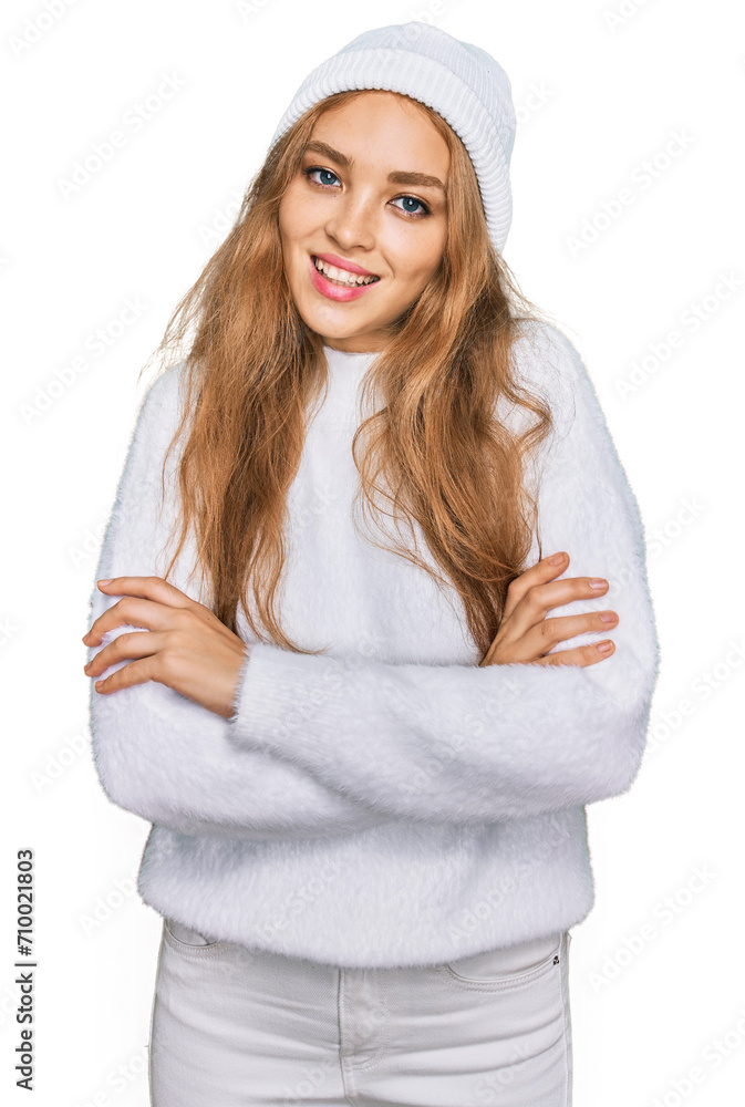 Young caucasian girl wearing wool sweater and winter cap happy face smiling with crossed arms looking at the camera. positive person. Young caucasian girl wearing wool sweater and winter cap happy face smiling with crossed arms looking at the camera. positive person.