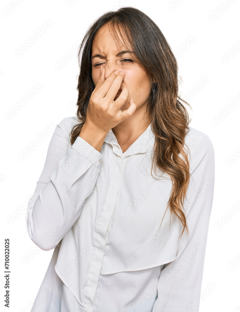 Young brunette woman wearing casual clothes smelling something stinky and disgusting, intolerable smell, holding breath with fingers on nose. bad smell Young brunette woman wearing casual clothes smelling something stinky and disgusting, intolerable smell, holding breath with fingers on nose. bad smell