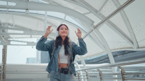Wallpaper Mural Happy young tourist asian woman wearing headphones and enjoying music on the urban street city, Smiling female listening to music and dancing alone. Torontodigital.ca