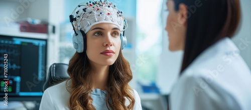 Female patient undergoing neurology testing with EEG headset, while doctor diagnoses disease. photo