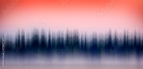 Blurred Sunrise Sunset on Lake with Mist Rising from Water Pine Trees and Mountains in Background