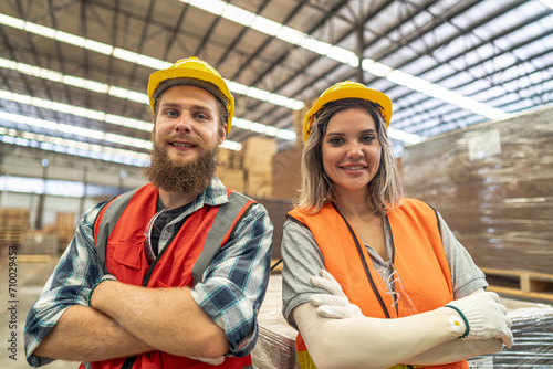 Team workers carpenter wearing safety uniform and hard hat working and checking the quality of wooden products at workshop manufacturing. man and woman workers wood in dark warehouse industry.