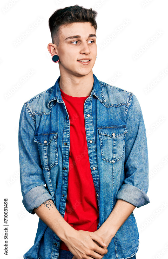 Young caucasian boy with ears dilation wearing casual denim jacket looking away to side with smile on face, natural expression. laughing confident. Young caucasian boy with ears dilation wearing casual denim jacket looking away to side with smile on face, natural expression. laughing confident.
