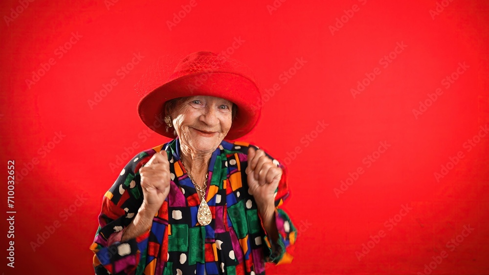 Funny fisheye portrait of elderly senior old woman with wrinkled skin looks at camera gives great idea gesture showing explosion of thinking posing isolated on red background. Funny fisheye portrait of elderly senior old woman with wrinkled skin looks at camera gives great idea gesture showing explosion of thinking posing isolated on red background.