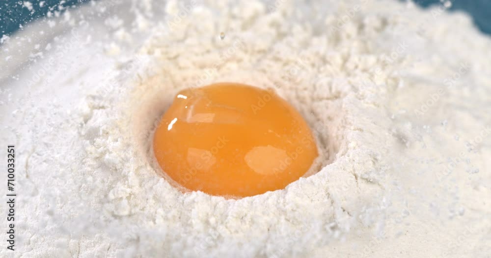 Super slow motion macro of fresh egg yolk is put in flour by artisan baker chef for preparation a dough while making homemade bread, pasta or pizza in traditional bakery kitchen. Super slow motion macro of fresh egg yolk is put in flour by artisan baker chef for preparation a dough while making homemade bread, pasta or pizza in traditional bakery kitchen.
