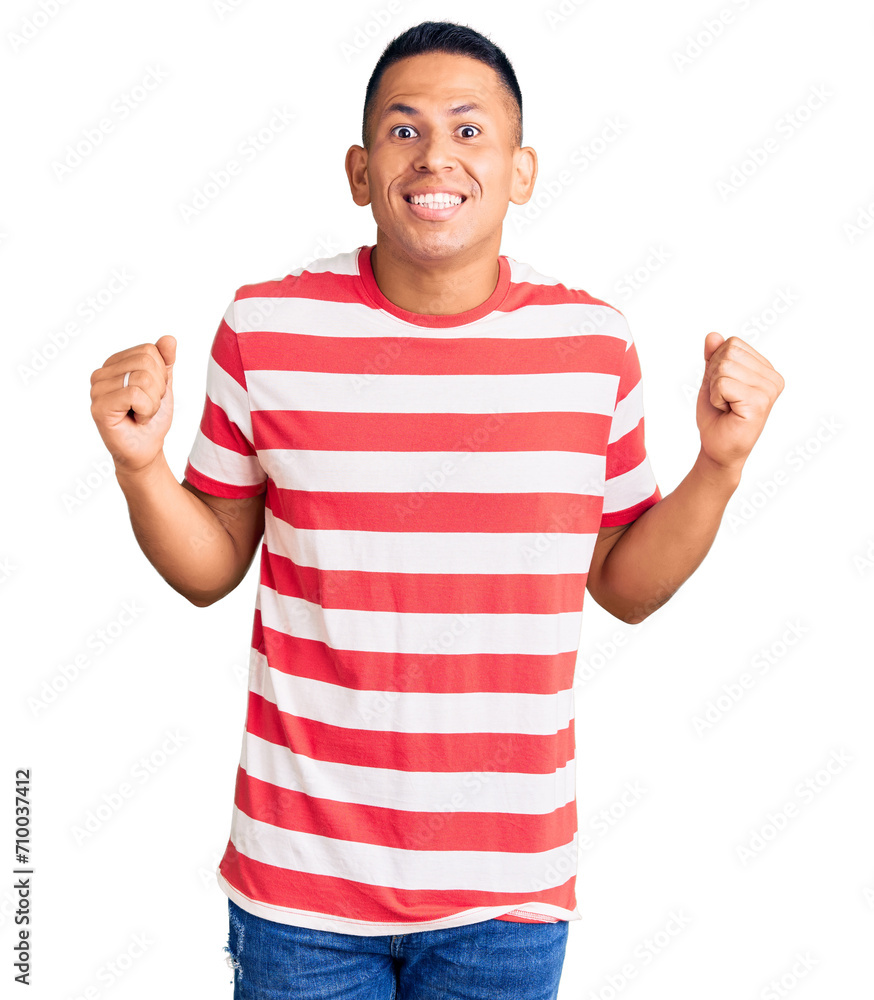Naklejka premium Young handsome latin man wearing casual clothes celebrating surprised and amazed for success with arms raised and open eyes. winner concept.
