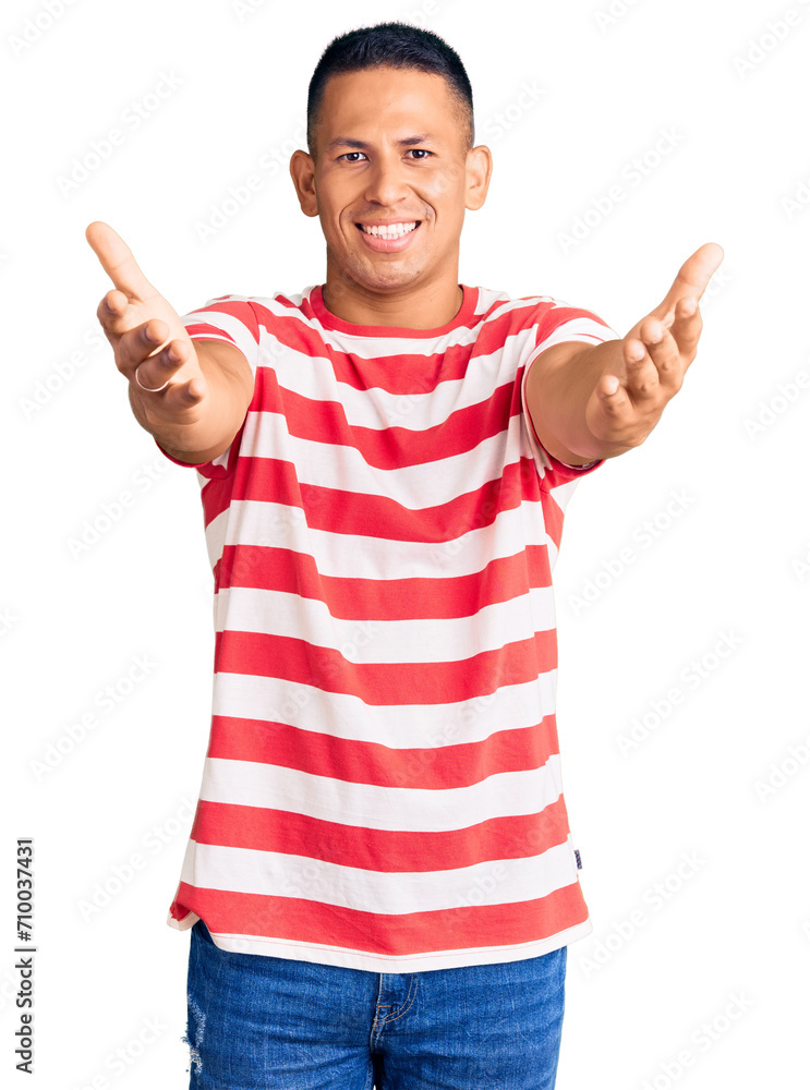 Young handsome latin man wearing casual clothes looking at the camera smiling with open arms for hug. cheerful expression embracing happiness. Young handsome latin man wearing casual clothes looking at the camera smiling with open arms for hug. cheerful expression embracing happiness.