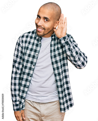 Hispanic adult man wearing casual clothes smiling with hand over ear listening an hearing to rumor or gossip. deafness concept.