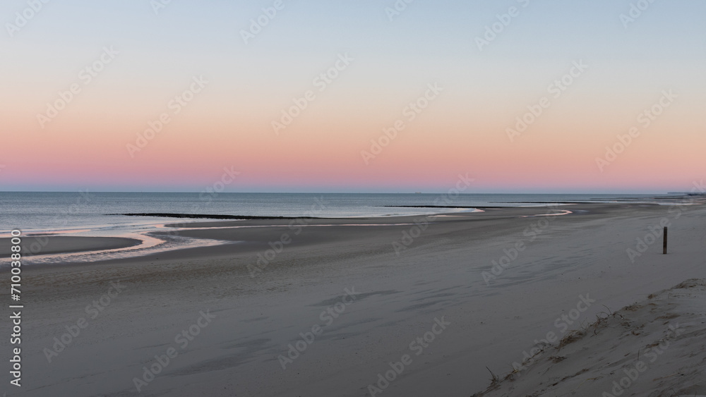 The beach of North Holland (Netherlands) looks deserted on this morning. The rising sun creates beautiful pastel colors.
