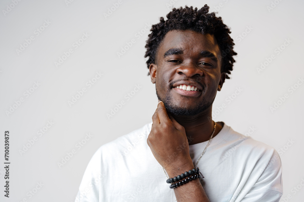 Portrait of a smiling young african man wearing white t-shirt standing over gray background Portrait of a smiling young african man wearing white t-shirt standing over gray background