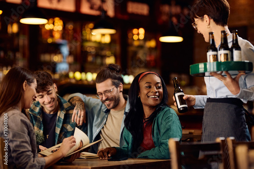Happy black woman and her friends getting their drinks from waitress in bar.
