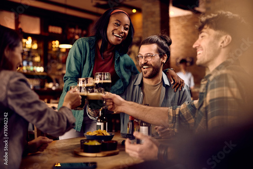 Young cheerful people having fun while toasting with drinks in pub.