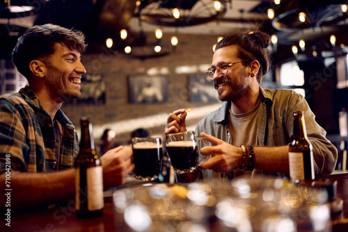 Happy men toasting while drinking beer in pub.