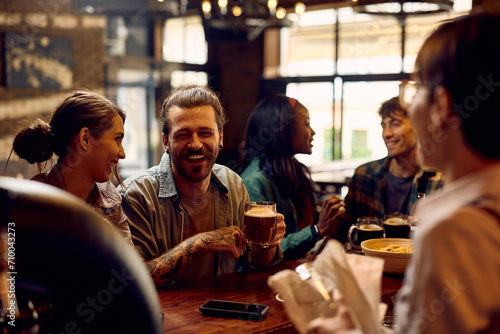 Cheerful man having fun while drinking beer with friends in pub. photo