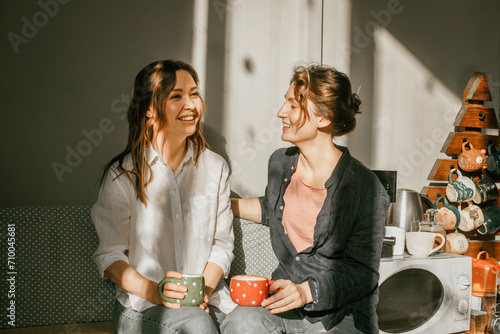 Time for intimate conversations: two women drinking tea in the sunshine in a cozy environment Girls friends talking over a cup of coffee photo