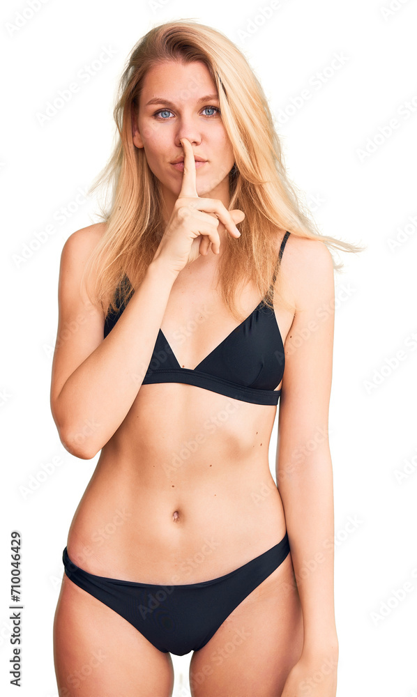 Young beautiful blonde woman wearing bikini asking to be quiet with finger on lips. silence and secret concept. Young beautiful blonde woman wearing bikini asking to be quiet with finger on lips. silence and secret concept.