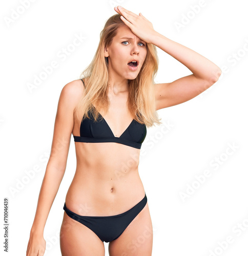 Young beautiful blonde woman wearing bikini surprised with hand on head for mistake, remember error. forgot, bad memory concept.