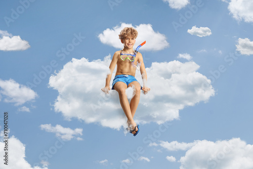 Boy in swimming shorts and a diving mask sitting on a cloud