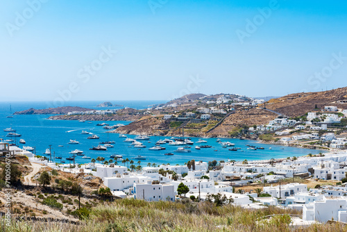 Fototapeta Naklejka Na Ścianę i Meble -  Mikonos, Greece - Ornos Beach. With umbrella and luxury beach chairs beds in front of blue ocean, Ornos is a family beach with crystal and shallow water.