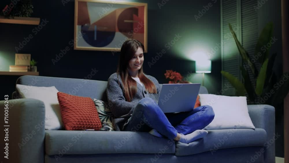 Woman relaxing sitting at couch. Female sitting at sofa with legs. Woman holding laptop and typing. Female using device for chatting. Smiling woman having spare time at home. Woman relaxing sitting at couch. Female sitting at sofa with legs. Woman holding laptop and typing. Female using device for chatting. Smiling woman having spare time at home.