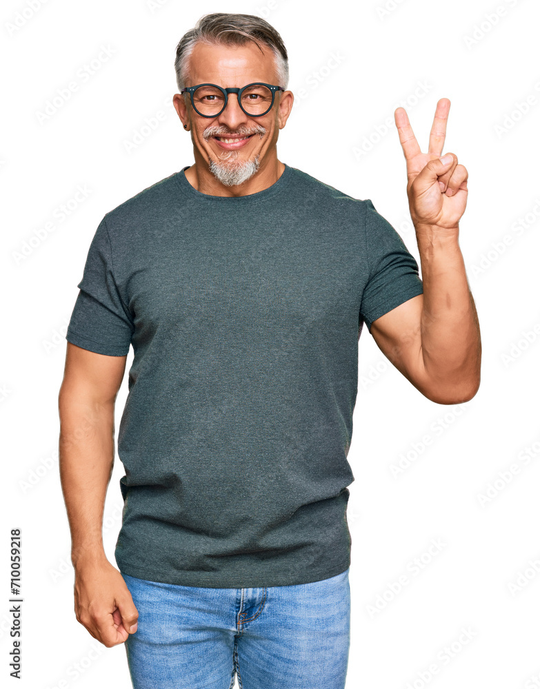 Naklejka premium Middle age grey-haired man wearing casual clothes and glasses smiling with happy face winking at the camera doing victory sign. number two.