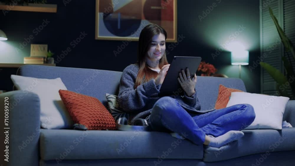 Smiling woman relaxing sitting at sofa. Happy female using gadget. Woman holding tablet and working. Female touching device screen. Cheerful woman looking at tablet. Staying at home. Smiling woman relaxing sitting at sofa. Happy female using gadget. Woman holding tablet and working. Female touching device screen. Cheerful woman looking at tablet. Staying at home.