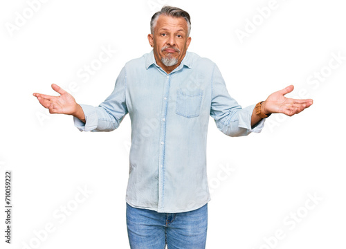 Middle age grey-haired man wearing casual clothes clueless and confused expression with arms and hands raised. doubt concept.