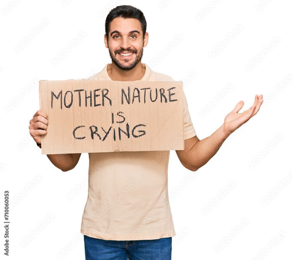 Young hispanic man holding mother nature is crying protest cardboard banner celebrating victory with happy smile and winner expression with raised hands Young hispanic man holding mother nature is crying protest cardboard banner celebrating victory with happy smile and winner expression with raised hands