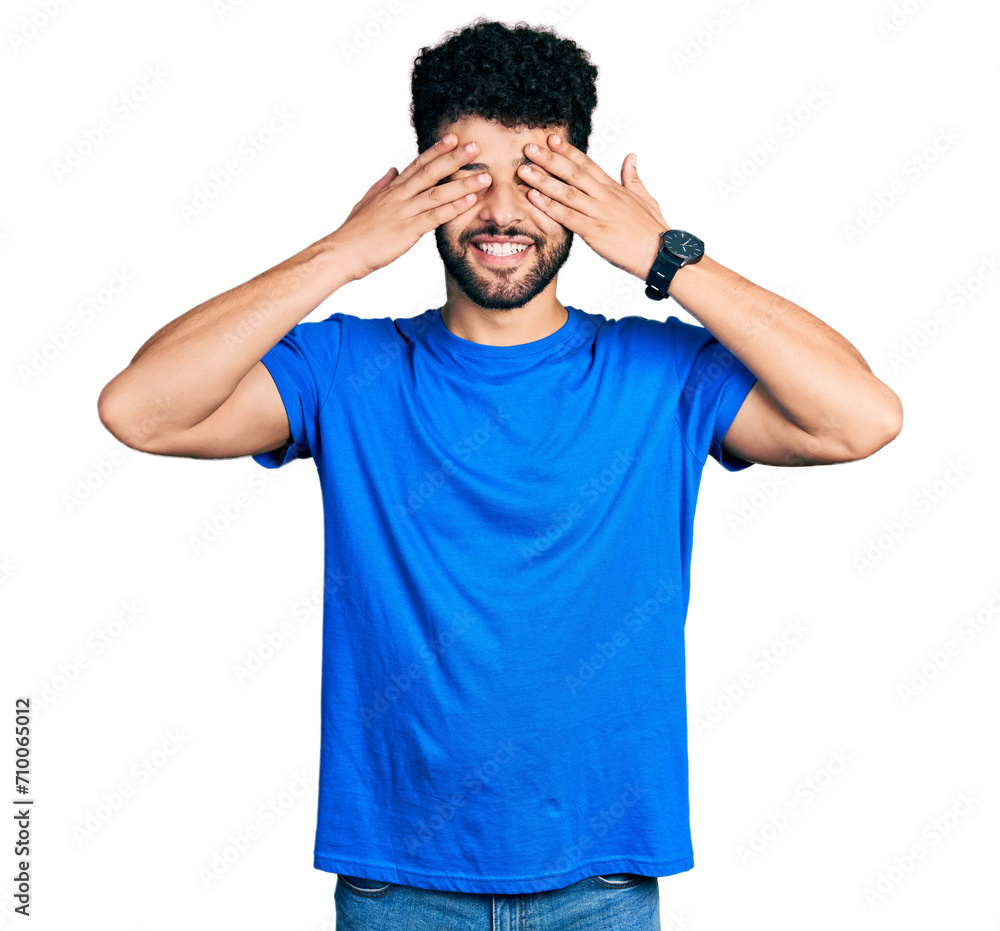 Young arab man with beard wearing casual blue t shirt covering eyes with hands smiling cheerful and funny. blind concept. Young arab man with beard wearing casual blue t shirt covering eyes with hands smiling cheerful and funny. blind concept.