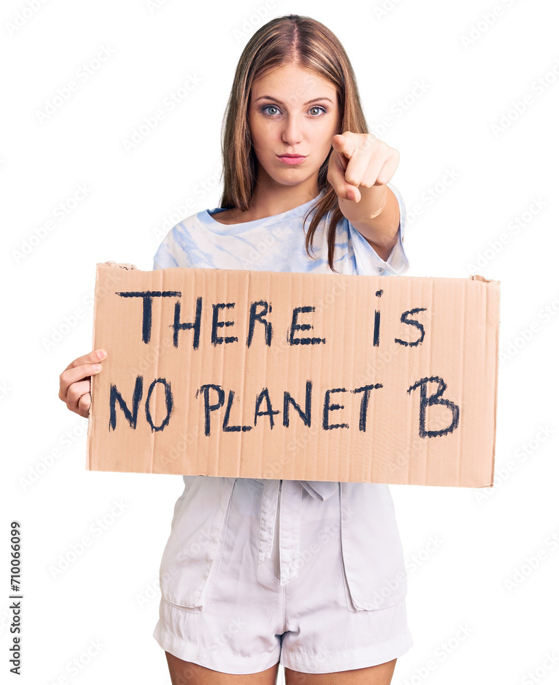 Young beautiful blonde woman holding there is no planet b banner pointing with finger to the camera and to you, confident gesture looking serious Young beautiful blonde woman holding there is no planet b banner pointing with finger to the camera and to you, confident gesture looking serious