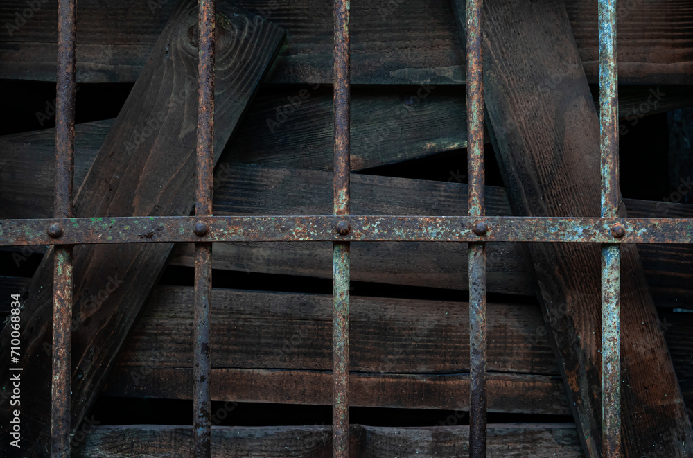 The window is boarded up and an old rusty grate is placed on top in an abandoned old fort it looks like a prison or arrest