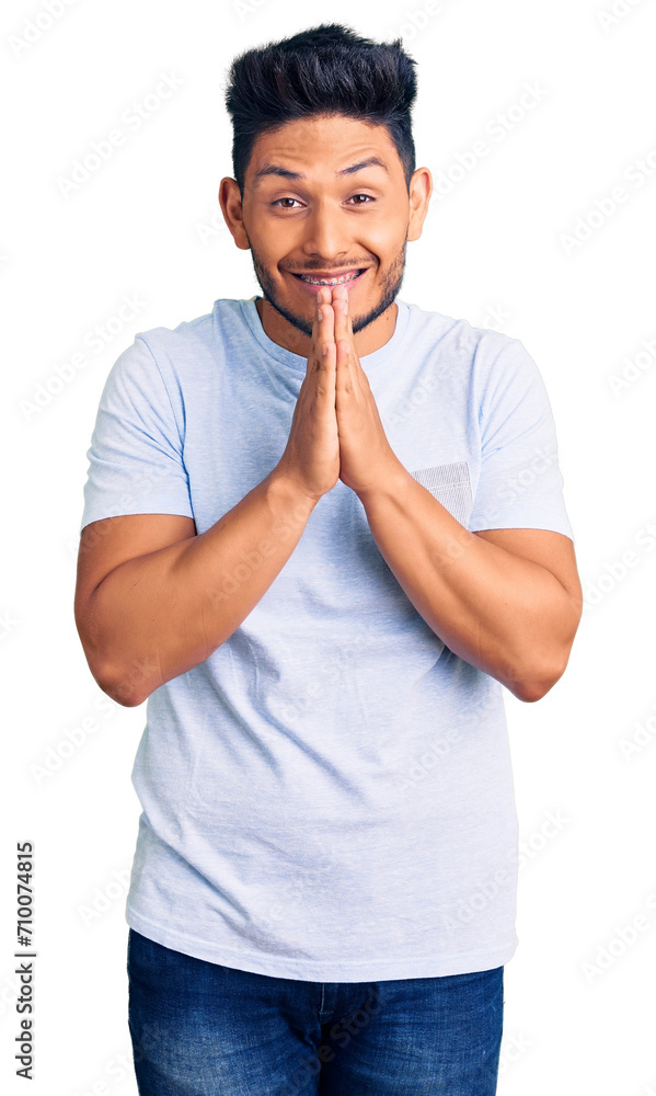 Handsome latin american young man wearing casual clothes praying with hands together asking for forgiveness smiling confident. Handsome latin american young man wearing casual clothes praying with hands together asking for forgiveness smiling confident.