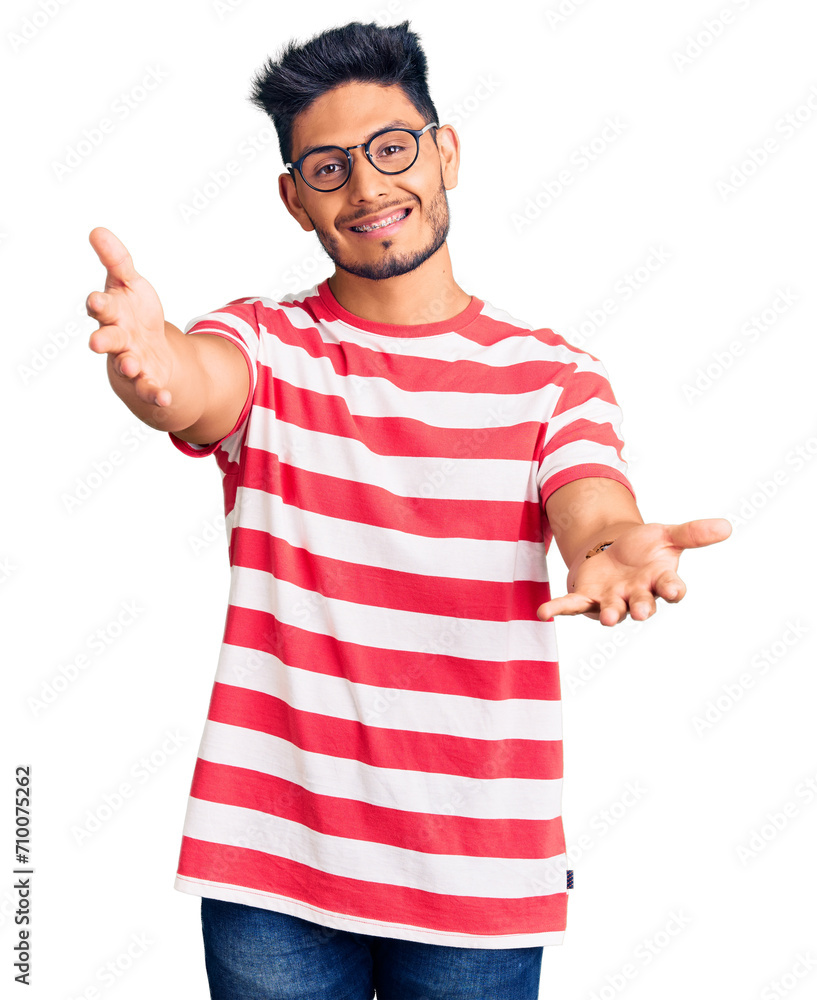 Handsome latin american young man wearing casual clothes and glasses looking at the camera smiling with open arms for hug. cheerful expression embracing happiness. Handsome latin american young man wearing casual clothes and glasses looking at the camera smiling with open arms for hug. cheerful expression embracing happiness.