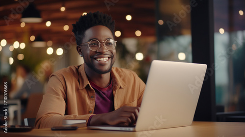 A young African-American freelancer man with a beaming smile and a smart casual light olive shirt poses confidently, with his clean, modern office space providing an ideal backdrop for productivity