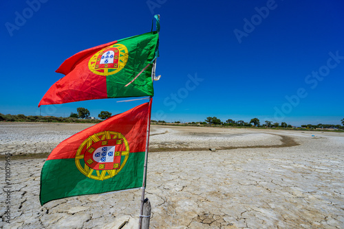 dry and cracked floor of dry river with portuguese national flag