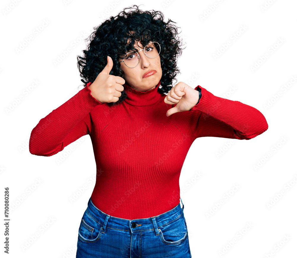 Young middle east girl wearing casual clothes and glasses doing thumbs up and down, disagreement and agreement expression. crazy conflict Young middle east girl wearing casual clothes and glasses doing thumbs up and down, disagreement and agreement expression. crazy conflict