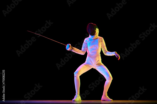 Martial arts and discipline. Fencing, martial art requiring discipline and strategy, perfect for related themes. Female athlete training over black background in neon. Concept of sport, competition